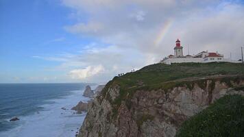 A lighthouse on the cliff overlooking the ocean with a rainbow video