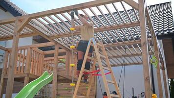 A man is working on a wooden play structure video