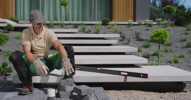A man is sitting on a stone patio with a tool video