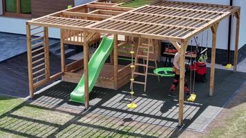 A wooden play structure with a slide and swings video