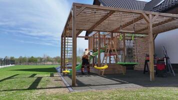 A play area with a swing set and a wooden pergola video