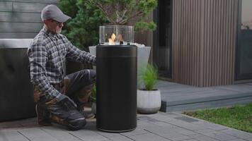 A man is kneeling next to a fire pit video