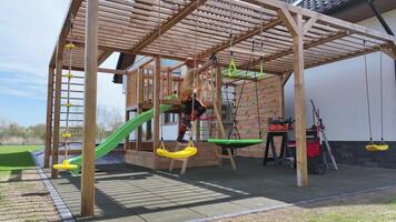 A wooden play structure with swings and slides video