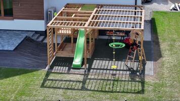 A wooden play structure with a slide and a swing video