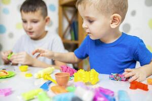 Children enthusiastically play with plasticine, play dough on white table photo
