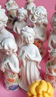group of white figurines sitting on top of a pink surface photo