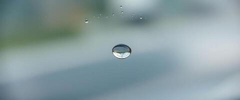 A drop of water on a window with a blurred background photo