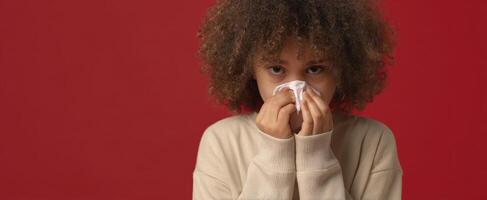 The girl with a tissue expressing discomfort and sadness against a red background. photo
