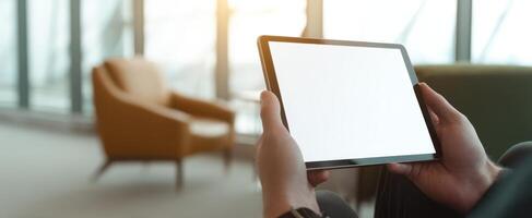 The tablet held in hands against a stylish indoor backdrop with bright lighting. photo
