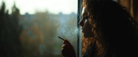 The woman gazing thoughtfully out of the window while smoking. photo