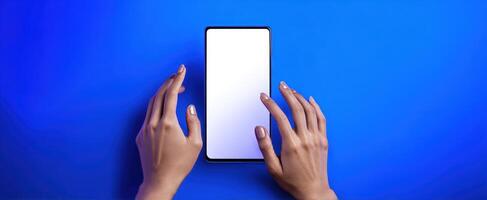 The smartphone held by hands against a vibrant blue background. photo