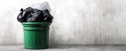 The green trash bin overflowing with black garbage bags on a concrete background photo