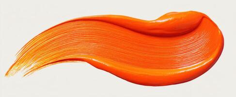 The vibrant orange paint brushstroke on a smooth surface. photo