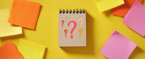 The notebook with question marks surrounded by colorful sticky notes. photo