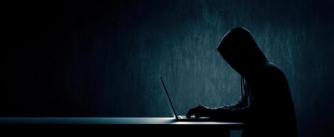 The mysterious hacker working in the shadows on a laptop. photo