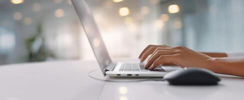 The hands typing on a laptop at a modern office workspace. photo