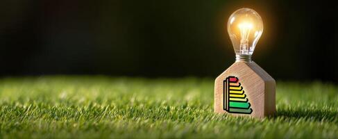 The illuminated light bulb resting on a stylish wooden house design. photo