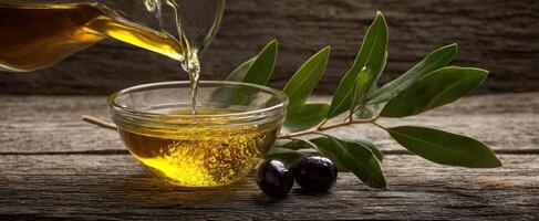 The olive oil pouring into a glass bowl with fresh olives and leaves. photo