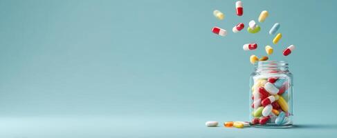 The colorful pills are pouring out of a glass jar on a blue background. photo