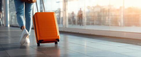 The traveler moving with an orange suitcase in a modern airport terminal. photo