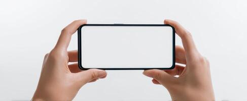 The hands holding a smartphone with a blank screen against a white background. photo