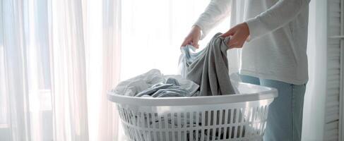 The woman organizing laundry in a bright, sunlit room near a window. photo