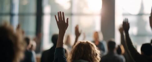 The audience actively engaging in a dynamic seminar with raised hands. photo