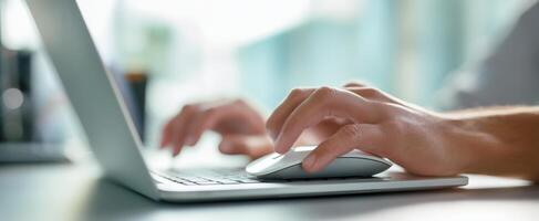 The hands using a mouse while typing on a laptop keyboard in a modern workspace. photo