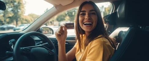 The happy woman in a car holds a credit card and smiles joyfully. photo