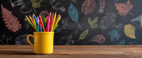 The vibrant yellow cup filled with colorful pencils on a wooden table. photo