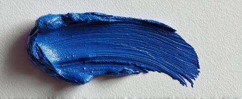The vibrant blue paint stroke on a textured canvas background. photo