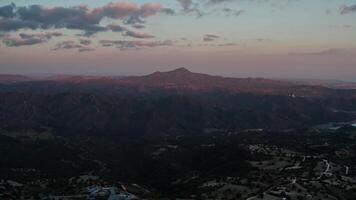 Vast mountainous landscape at twilight with rolling hills, a prominent mountain, and a sky transitioning from deep blue to soft purple and pink, evoking serenity and natural beauty video