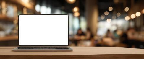 The laptop on a rustic wooden table in a modern cafe setting. photo