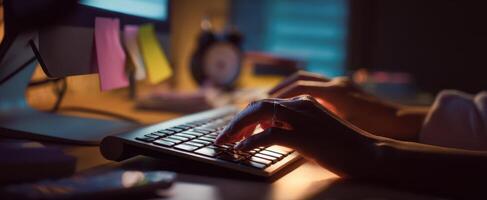 The focused hands typing on a keyboard in a dimly lit workspace. photo