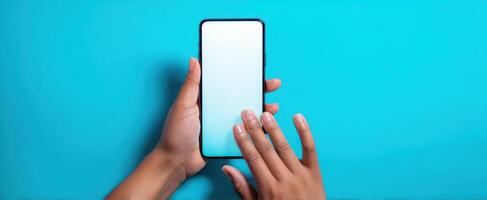The smartphone in a person's hand against a blue background. photo