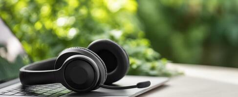 The sleek black headset resting on a modern laptop in a serene environment. photo