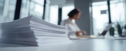 The stack of paperwork in an office environment with a focused employee working. photo