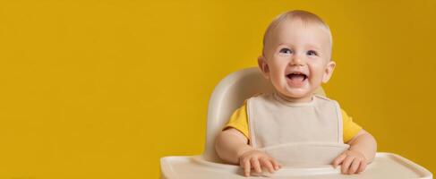 The joyful baby smiling in a highchair against a vibrant yellow background. photo