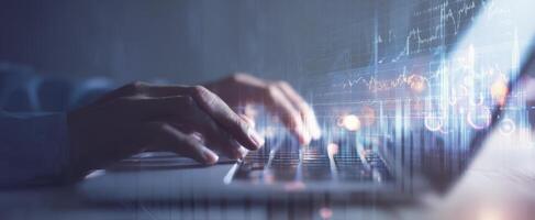 The hands of a professional typing on a laptop with digital graphs. photo