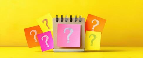 The colorful notebook surrounded by sticky notes with question marks for creativity. photo
