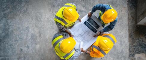 The construction team reviewing plans with a laptop and blueprints on site. photo