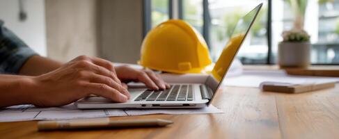 The laptop on a construction desk with a hardhat nearby, symbolizing work. photo