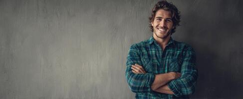 The smiling man in a plaid shirt against a textured backdrop. photo