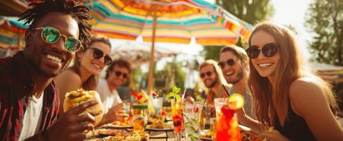 The joyful gathering of friends enjoying food and drinks outdoors under umbrellas. photo