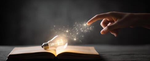 The hand igniting creativity with a magical lightbulb above an open book. photo