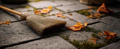 The broom resting on a cobbled path surrounded by fallen autumn leaves. photo