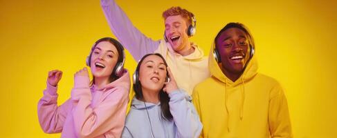 The joyful group of friends enjoying music with colorful headphones against a vibrant backdrop. photo