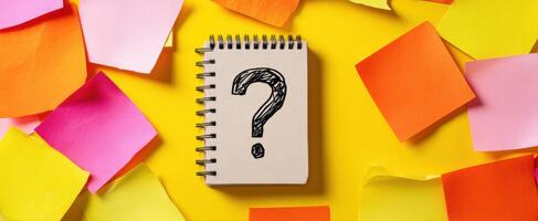 The question-filled notebook surrounded by vibrant sticky notes on a yellow background. photo