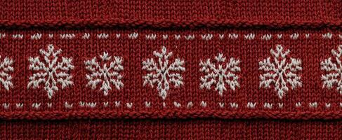 The vibrant knit fabric featuring intricate snowflake designs in red and white. photo