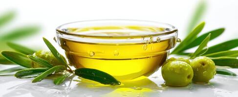 The olive oil in a glass bowl surrounded by fresh leaves and olives. photo